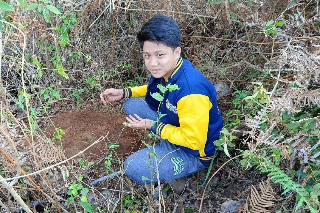 Hans (GEMAKU) sedang Menanam Bibit Pohon Kehidupan di Area Kemah.