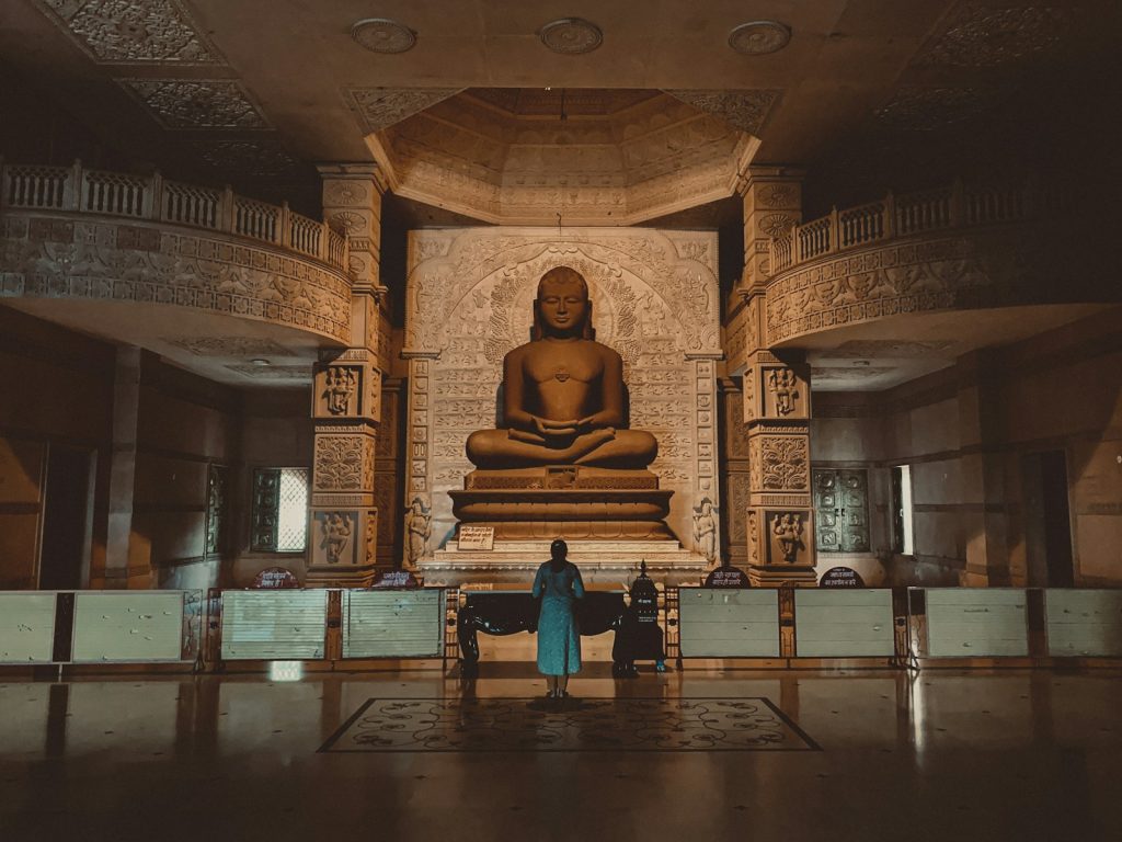 two people standing in front of a buddha statue