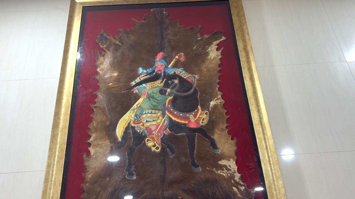 Bingkai gambar Dewa Kwan Kong berlatar kulit hewan.